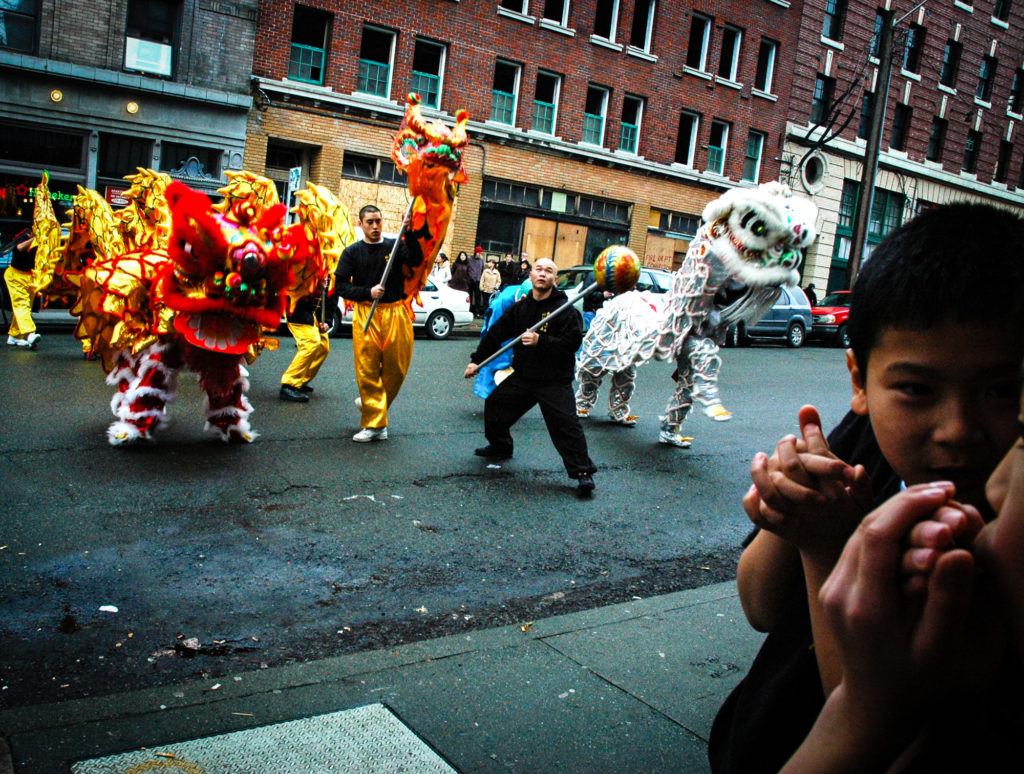 Two boys chat and keep their hands warm watching the New Years Dragon and Lions Dance